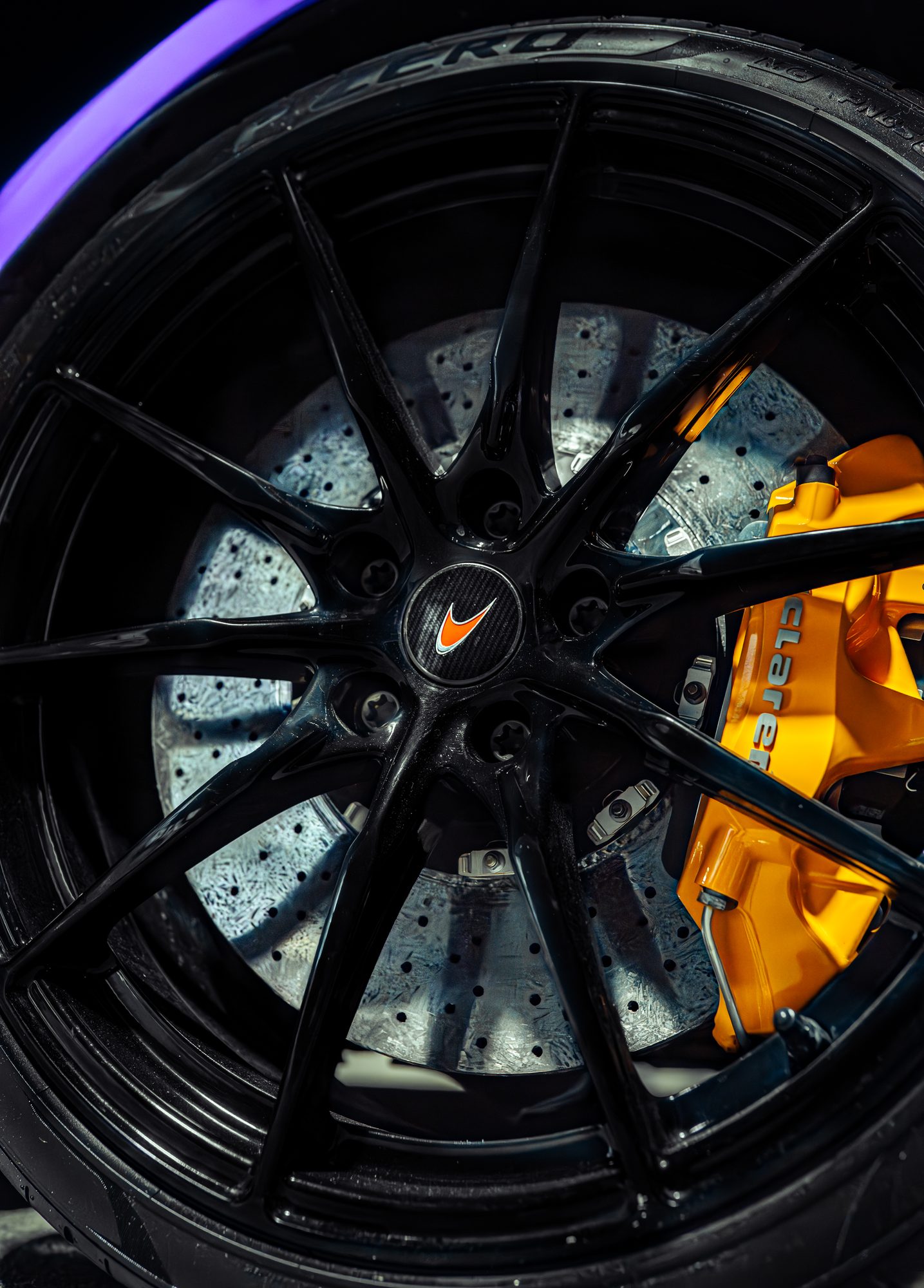 Yellow brake calipers behind a gloss black McLaren wheel, refinished by Restyle Miami